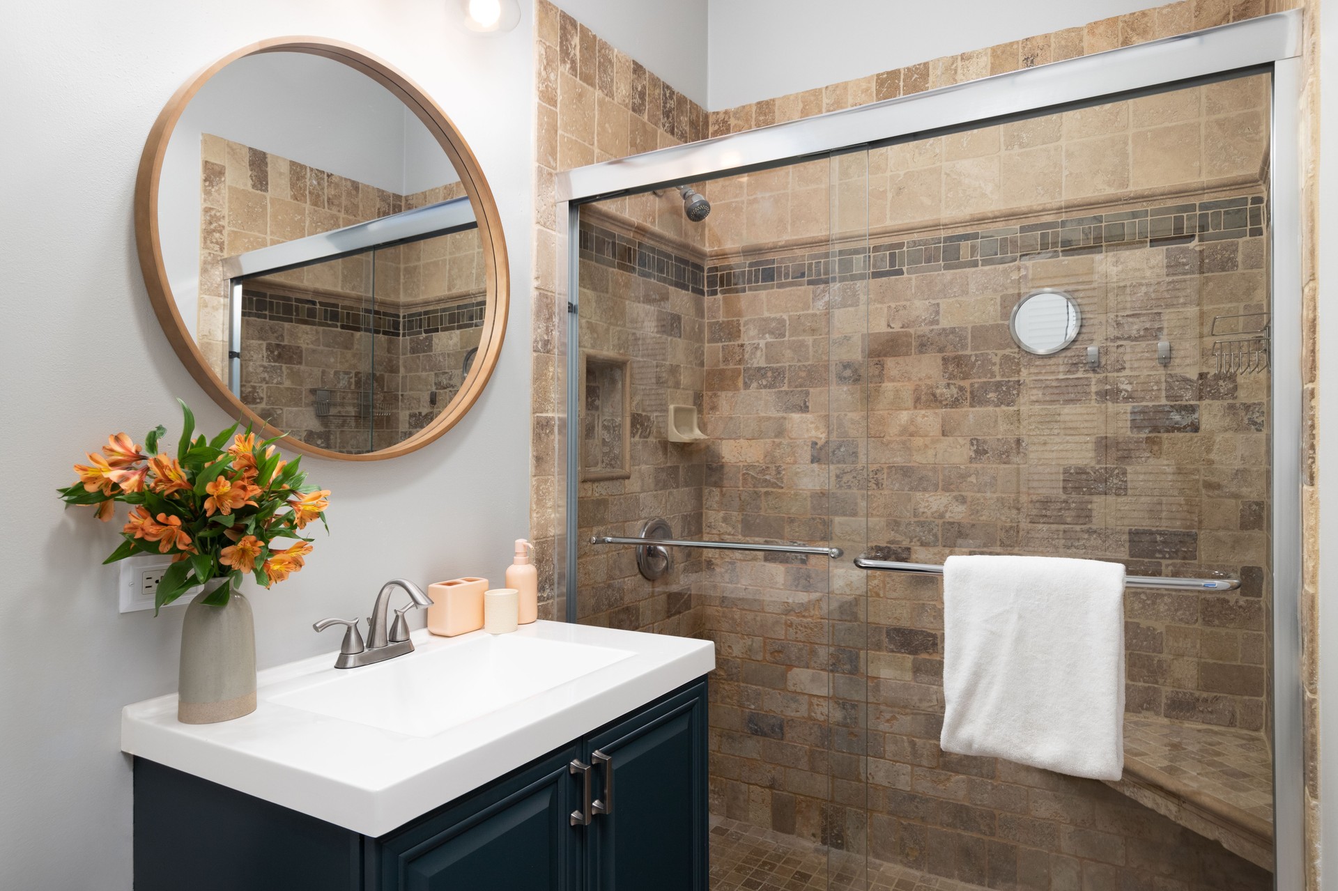 A bathroom with a blue cabinet and a stone tiled shower.